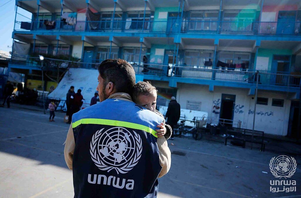 Un trabajador de la UNRWA consuela a un niño en un refugio escolar del campamento de Nuseirat, Gaza