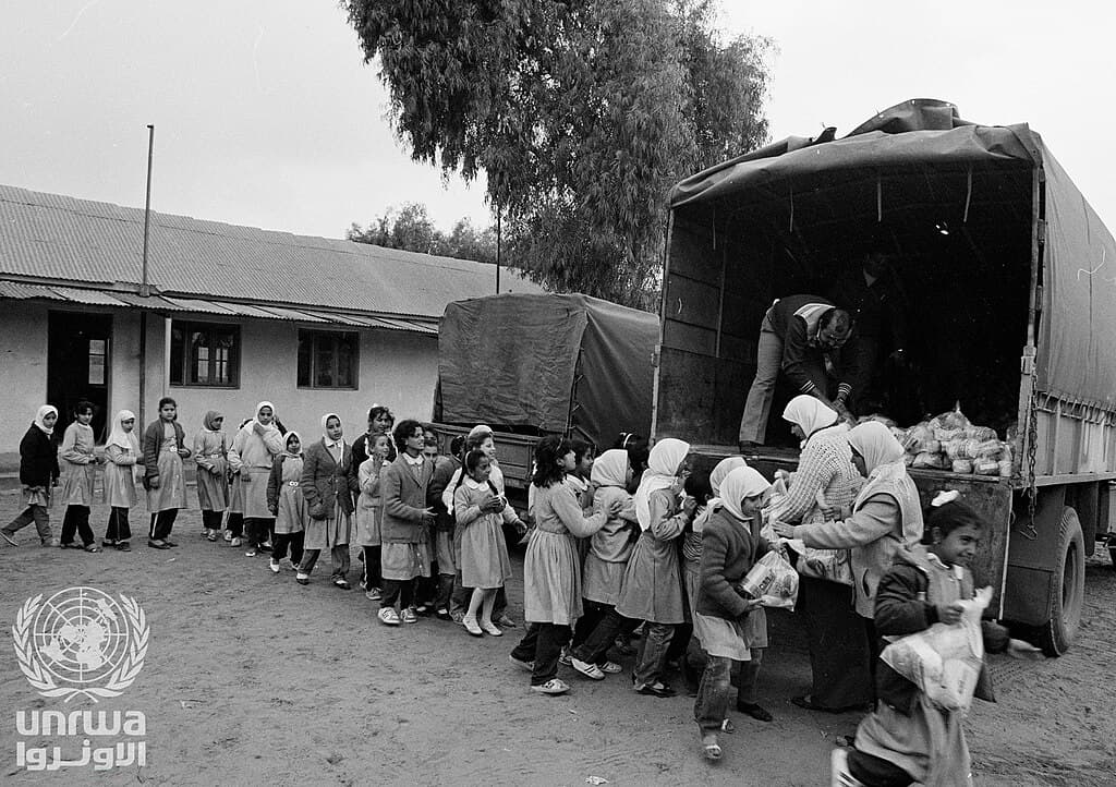 Alumnas hacen fila para recibir paquetes de alimentos de la UNRWA en Gaza